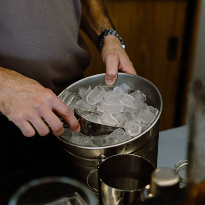Ice being scooped into a metal container, commercial kitchen cleaning service at work, cold beverage preparation, professional kitchen maintenance, C&W Commercial cleaning services.